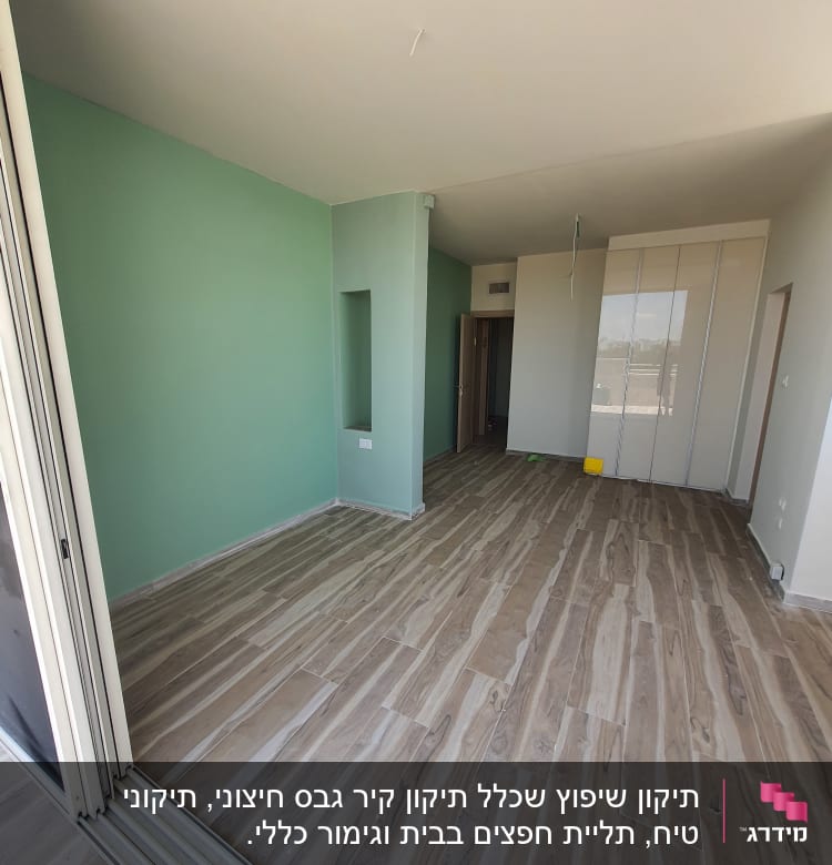 חדר עם רצפת עץ חדשה וקיר צבוע בירוק